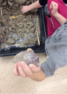 Kid showing the huge amethyst crystal they found excavating for fossils at a Dinosaurs Rock Birthday Party