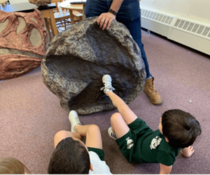 Kids comparing the size of their foot to a Cast of a T-REX Footprint