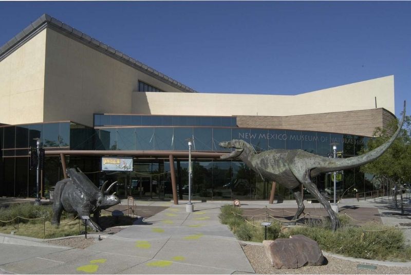 New Mexico Museum of Natural History and Science outside of building with a Triceratops and T-REx sculpture in front