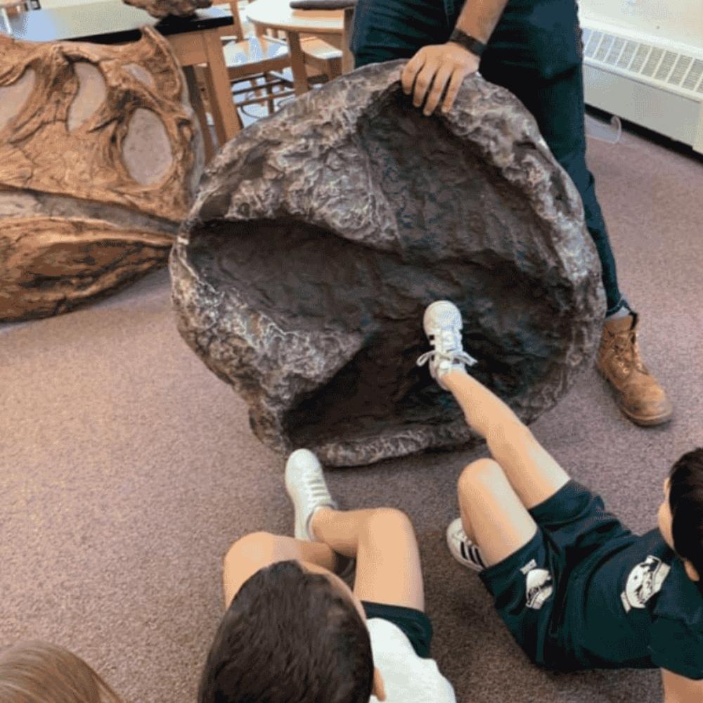 kids comparing their foot to a t-rex footprint in a classroom setting